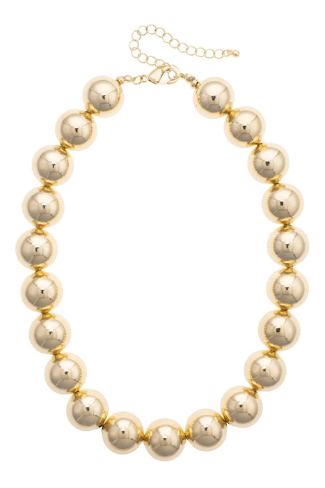 The Polka Dot Press Marjorie beaded necklace featuring chunky, shiny gold resin beads with an adjustable 16-inch chain.